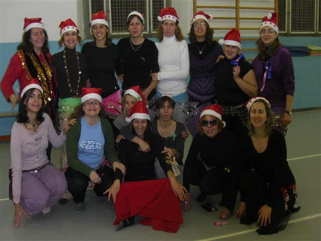 Tutto il gruppo delle danzatrici con in testa dei cappellini di Babbo Natale e sui fianchi delle cinture colorate con dei campanellini,